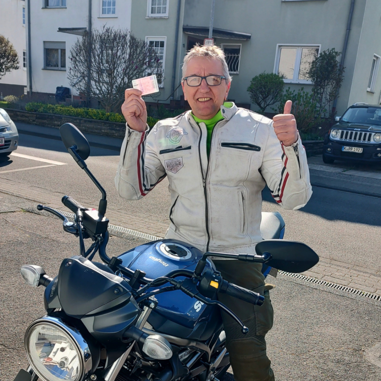 Fröhlicher Fahrschüler auf Motorrad nach Prüfung