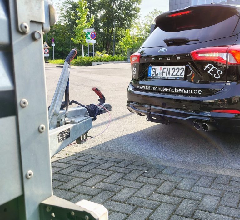 Schwarzes Auto mit Anhängerkupplung auf einem Straßenparkplatz.